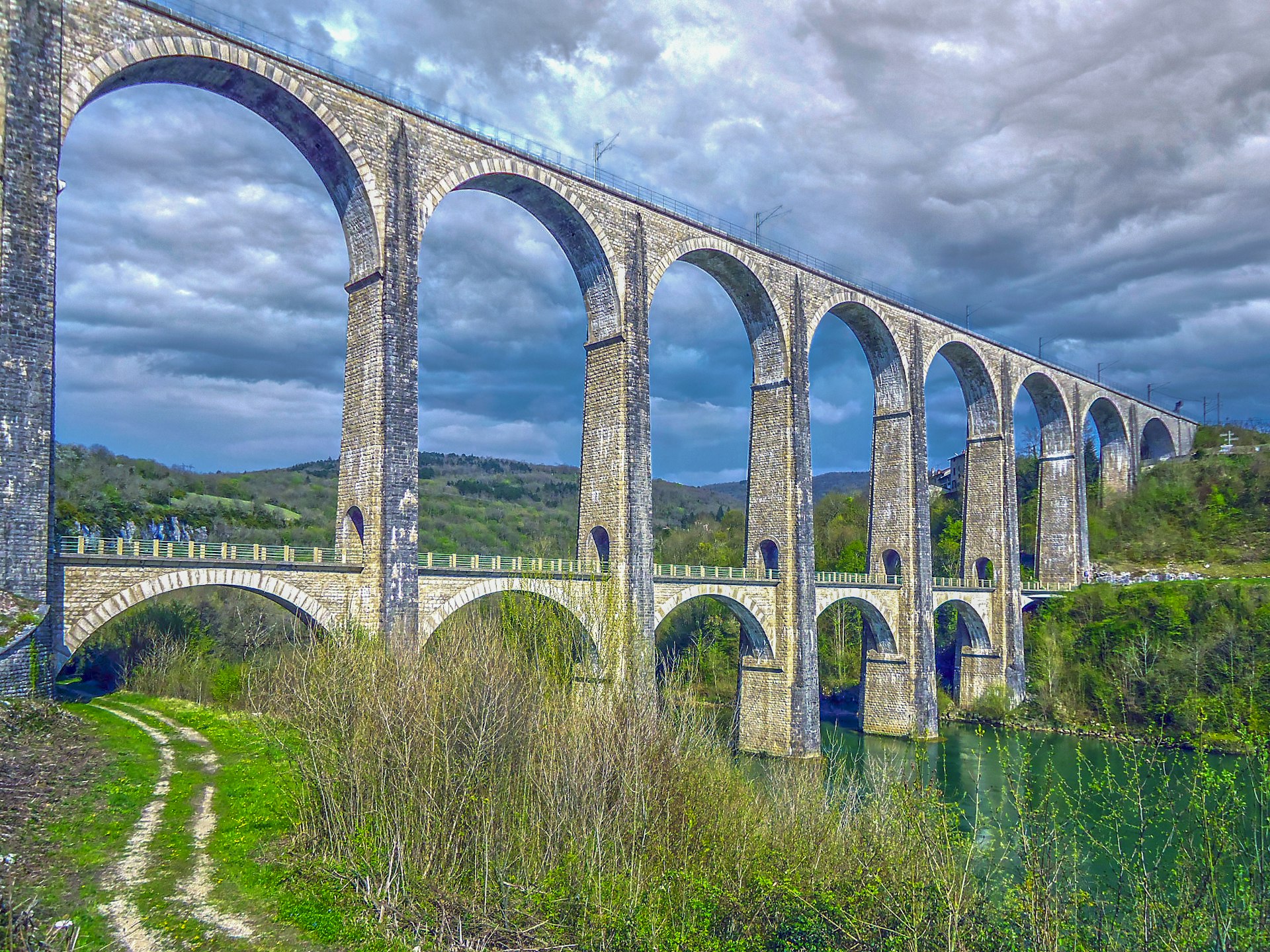 a large stone bridge over a river under a cloudy sky